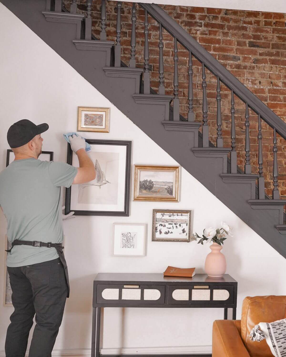 Sparkling Clean technician dusting picture frames along a staircase